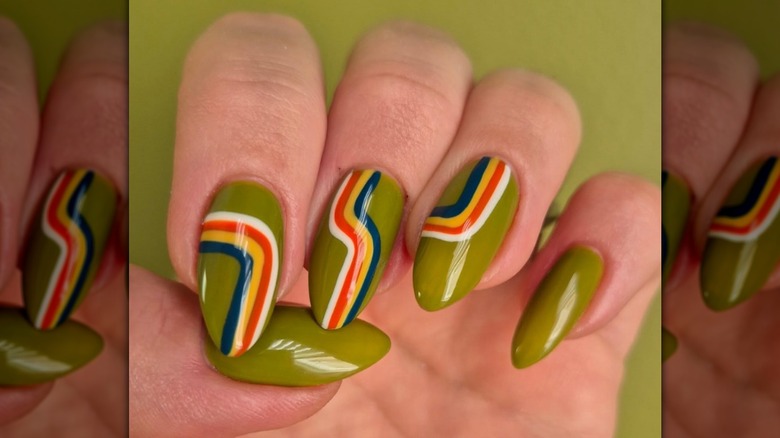 Close up shot of an olive green manicure with white, red, yellow, and blue stripes.