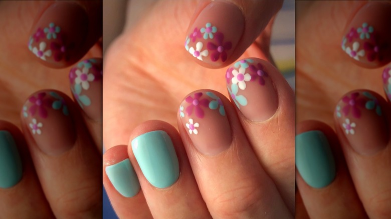 Close up image of a manicure with two light blue nails and three nails with pink and blue flowers.