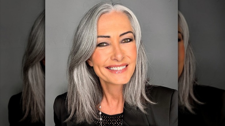 A woman with medium-length gray hair smiling and wearing a black top and blazer.