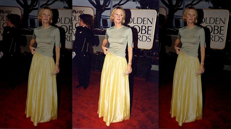 Meg Ryan posing on the red carpet wearing a yellow satin skirt.