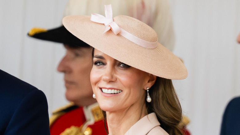 Kate Middleton smiles while wearing a sunhat and pearl earrings