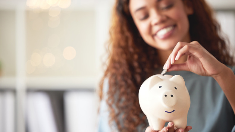 Woman putting money in piggybank