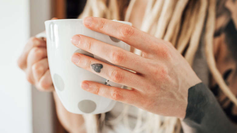 woman with tattoo holding cup