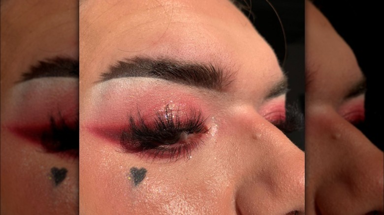 Close up of man wearing red winged eyeshadow