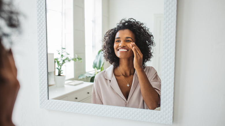 Girl looking at herself in the mirror after applying skincare