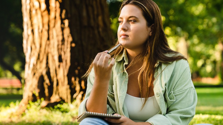 person thinking with notebook in hand