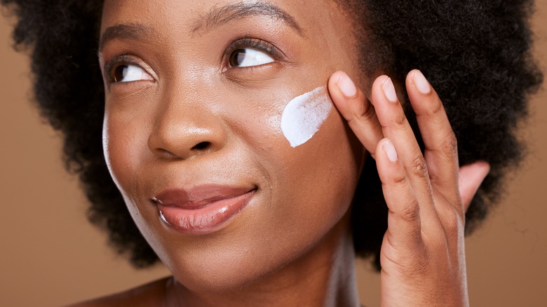 woman apply cream to her skin