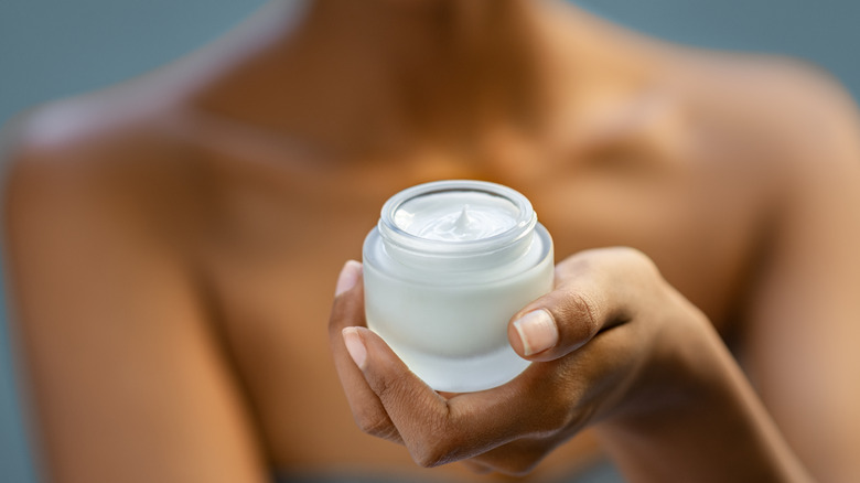 person holding jar of cream