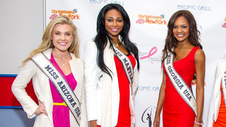 Erika Kirk wearing a Miss Arizona sash posing for a picture with other beauty queens