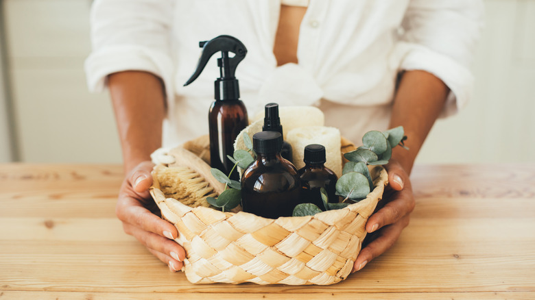 Woman holding a wicker basket of cleaning supplies.