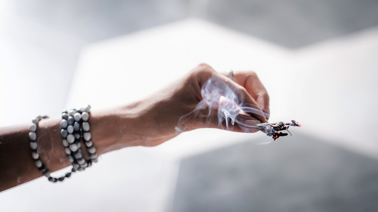 Woman's hands holding a burning sage bundle.