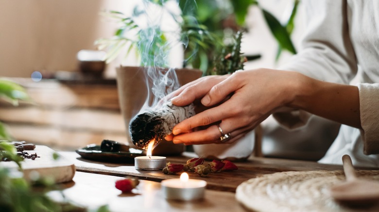 Hands holding a burning sage bundle