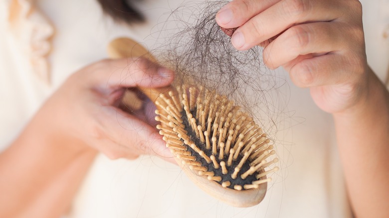 woman pulling hair out of brush
