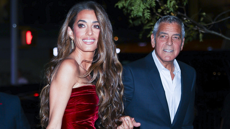 Amal and George Clooney arrive at an event, smiling