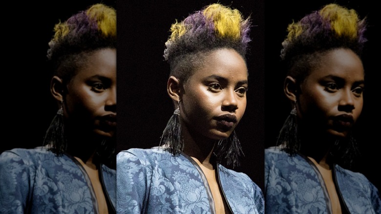 A person with a colored pompadour and fringe earrings