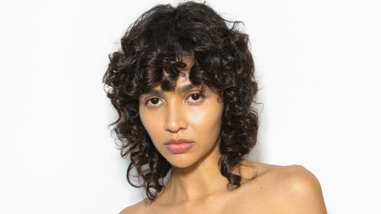 A person posing with a curly shag haircut