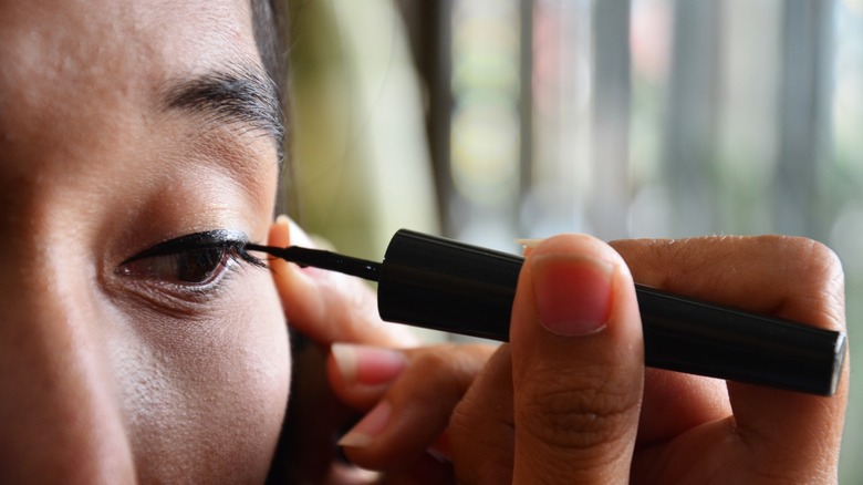 woman applying eyeliner to lash line