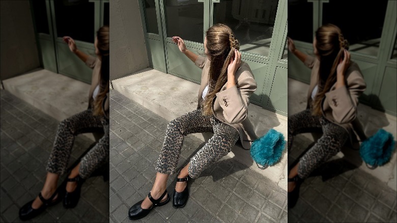 Woman sitting, wearing animal-print pants