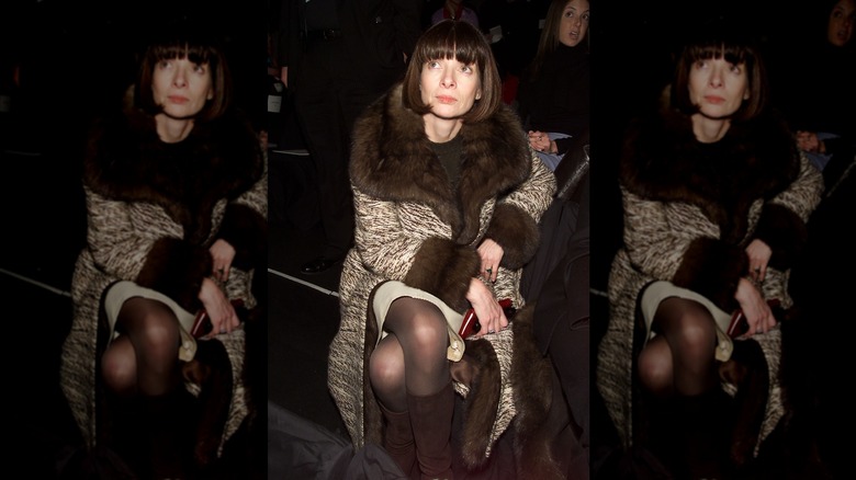 Anna Wintour looks up with dark brown hair wearing a fur-trimmed jacket