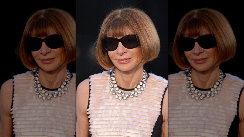 Anna Wintour smiles wearing black sunglasses and a crystal necklace