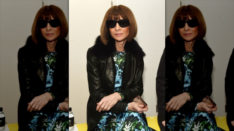 Anna Wintour poses with brown hair wearing sunglasses and a leather jacket