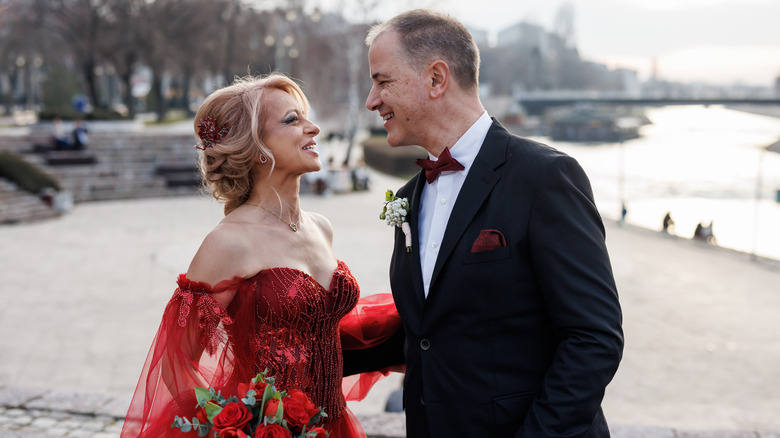Bride in red wedding dress smiles at groom
