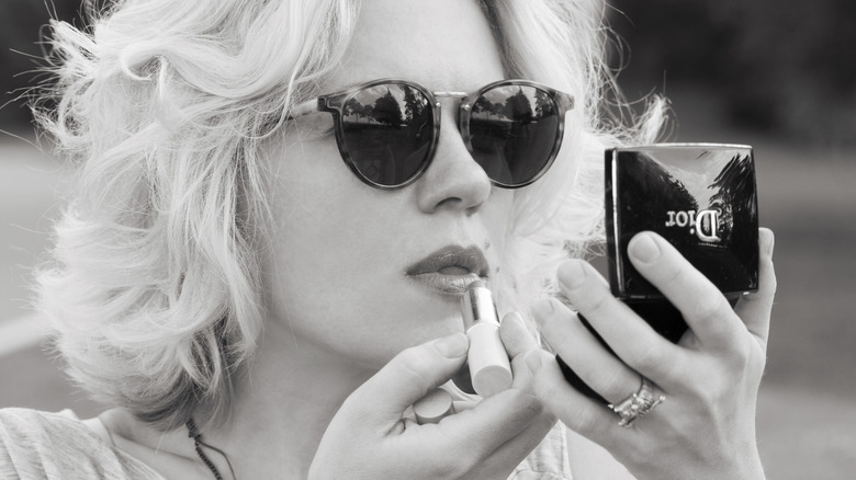 blonde woman applying dior lipstick
