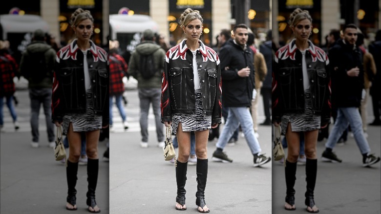 Person in denim jacket and black thong boots