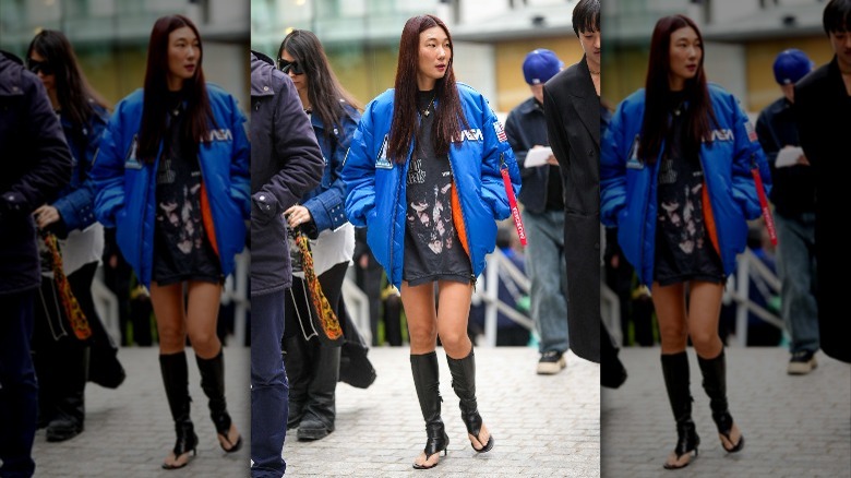 Person in blue bomber jacket and thong boots