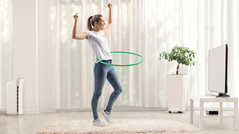 young woman hula hooping in a living room
