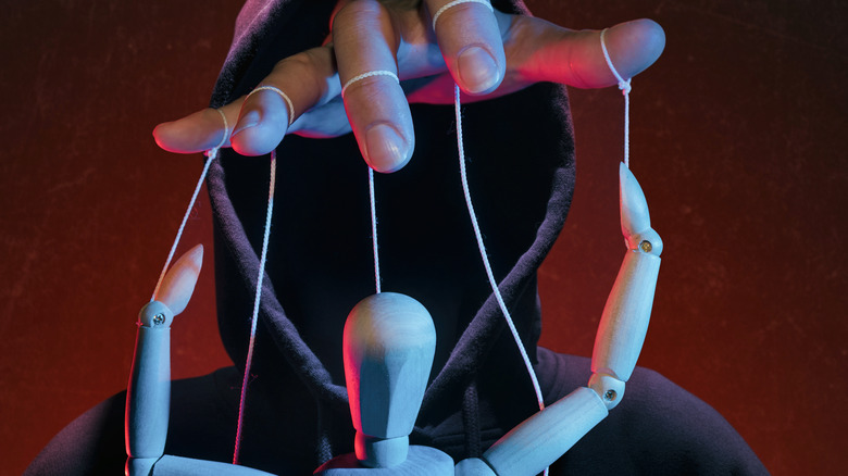 Hang with strings controlling a wooden puppet