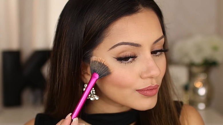 Woman applying highlighter with brush