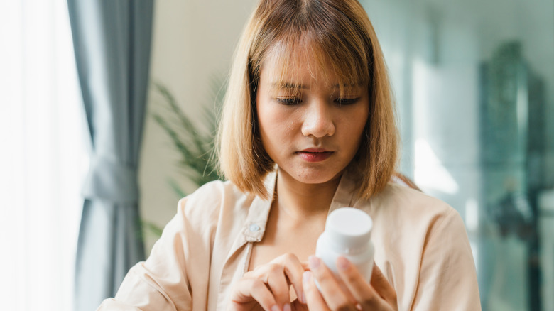 woman looking at medicine bottle