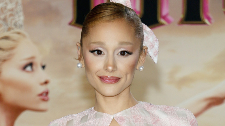 Ariana Grande posing in a pink dress with bleached hair to promote 