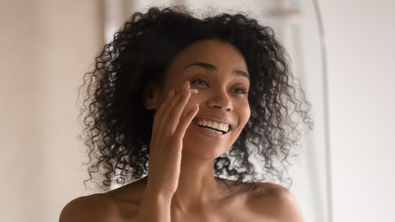 smiling woman applying eye cream