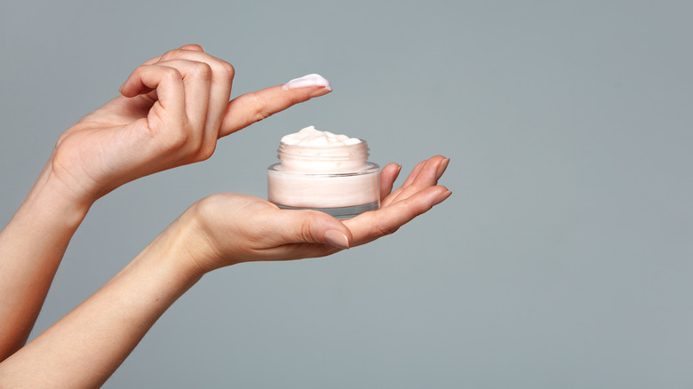hand holding pot of skin cream
