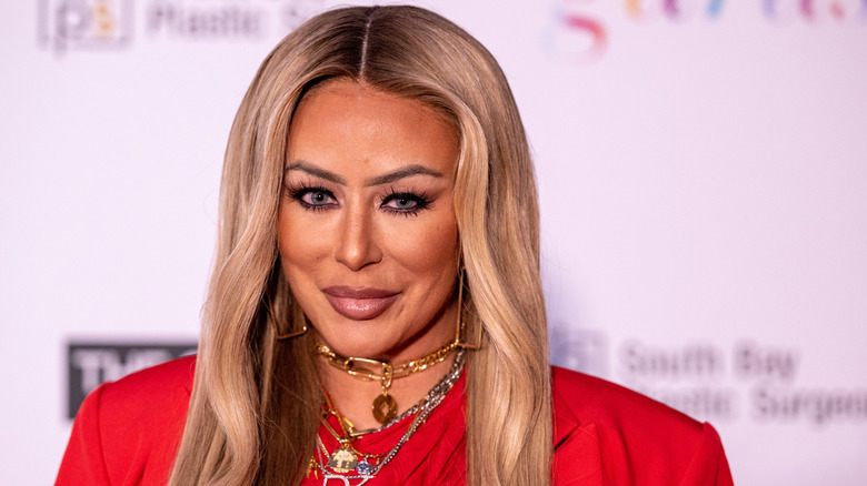 Aubrey O'Day in a red outfit with gold and silver jewelry