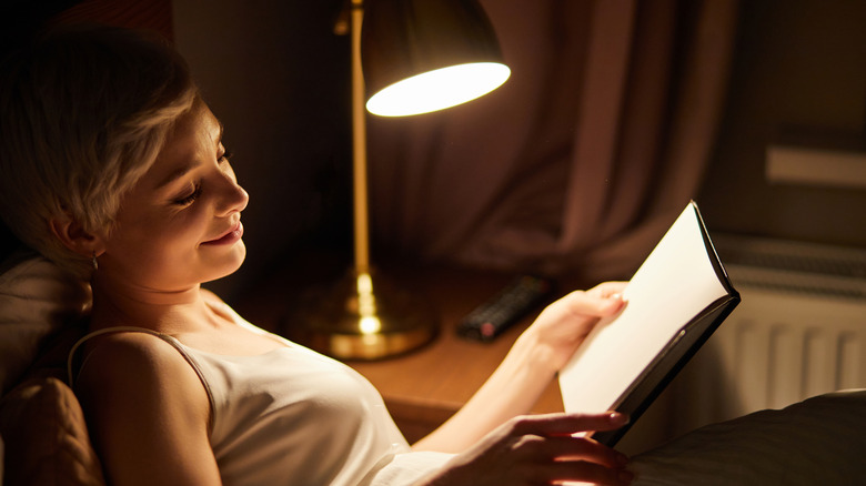 woman reading book in bed