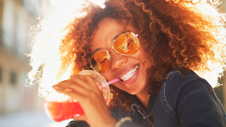 Woman sipping beverage in sunshine