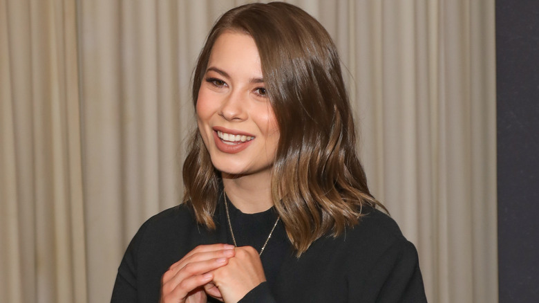 Bindi Irwin smiling while wearing a black top and necklace