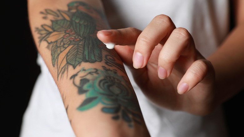 Woman applying cream to tattoo