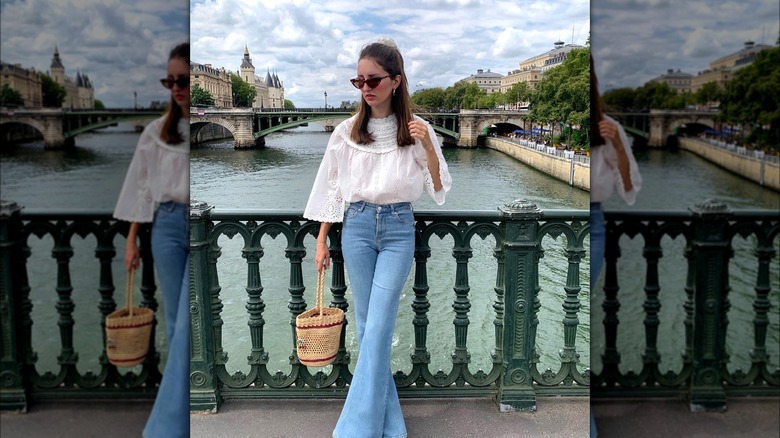 Girl wearing a flowy white top with boot-cut jeans.
