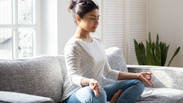 Woman doing breathing exercise on sofa