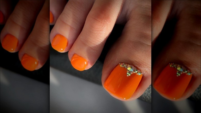 Woman with an orange pedicure and gems