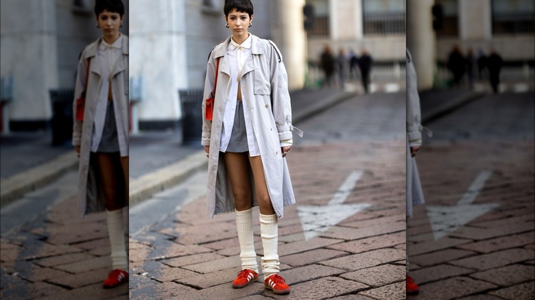 Woman wearing trench coat and red sneakers