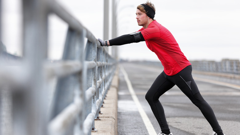 Man stretching calf while braced