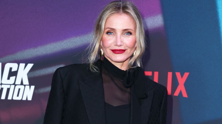Cameron Diaz smiling with red lipstick in a monochromatic black outfit