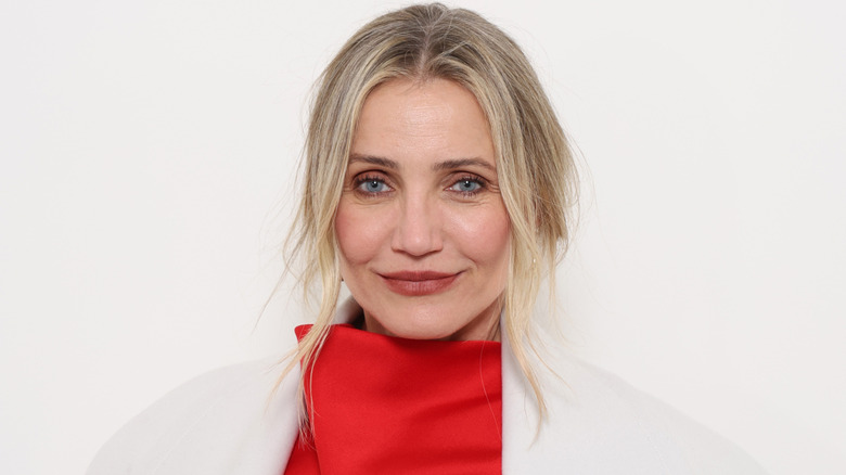 Actor Cameron Diaz wearing a white coat and red turtleneck dress