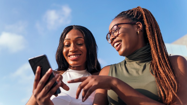 two women smiling at phone