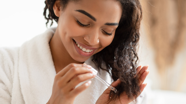 woman applying oil to hair
